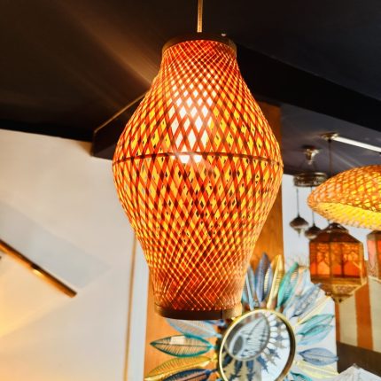 Bring warmth and artisanal charm to your interiors with our Ember Weave Bamboo Pendant Lamp, a stunning fusion of traditional craftsmanship and modern aesthetic. This handcrafted light fixture features an elegant hourglass silhouette with a crisscross diamond weave pattern, allowing a warm, glowing light to gently filter through the natural bamboo. Dyed in fiery amber and earthy red tones, it casts a rich, inviting ambiance ideal for cozy cafés, contemporary homes, or boutique spaces. Each piece is meticulously handwoven by skilled artisans, making every lamp unique in character and soul.