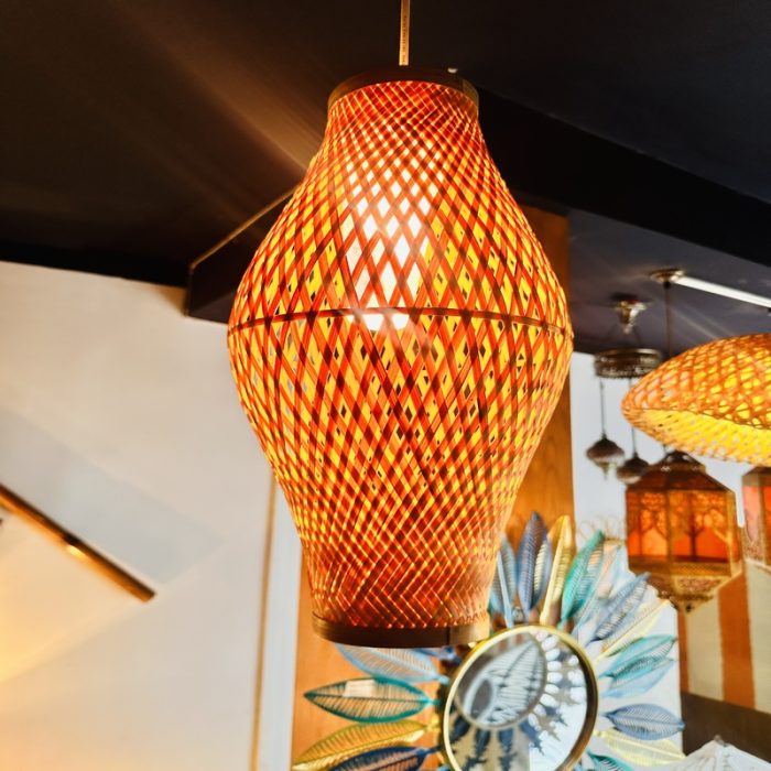 Bring warmth and artisanal charm to your interiors with our Ember Weave Bamboo Pendant Lamp, a stunning fusion of traditional craftsmanship and modern aesthetic. This handcrafted light fixture features an elegant hourglass silhouette with a crisscross diamond weave pattern, allowing a warm, glowing light to gently filter through the natural bamboo. Dyed in fiery amber and earthy red tones, it casts a rich, inviting ambiance ideal for cozy cafés, contemporary homes, or boutique spaces. Each piece is meticulously handwoven by skilled artisans, making every lamp unique in character and soul.